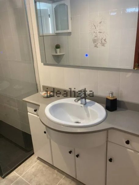 Baño moderno con lavabo, espejo y ducha de cristal. Decoración minimalista.